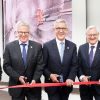 Five suited men are cutting a ribbon at ABB headquarters Australia.