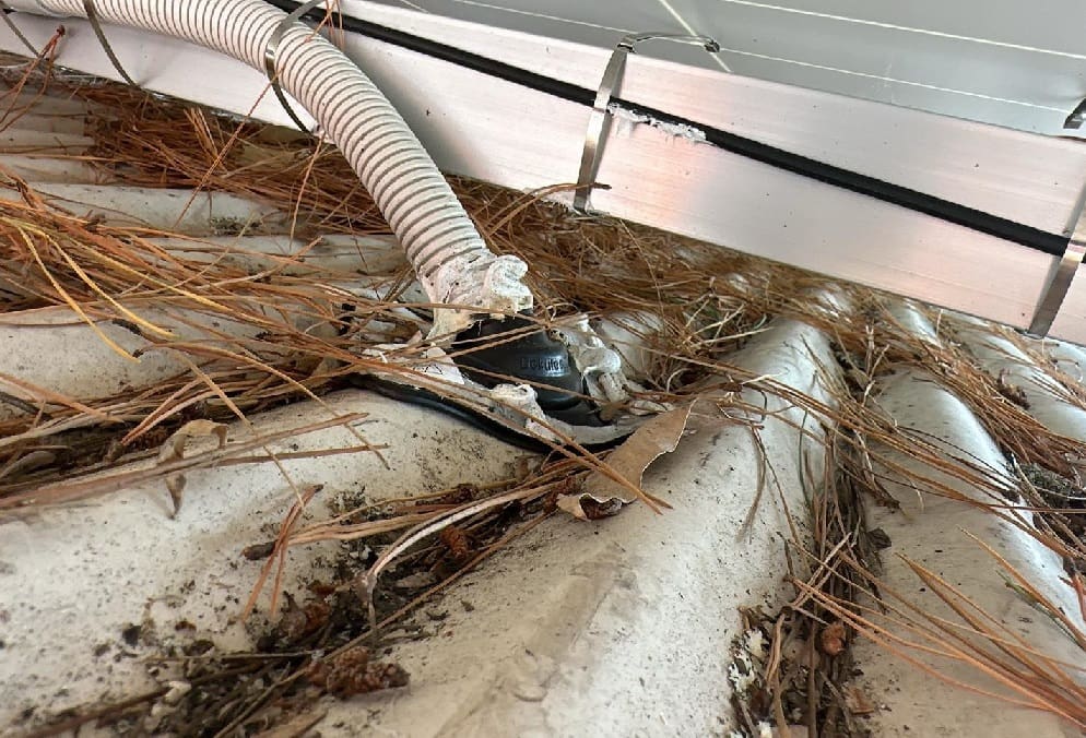 A damaged cable under a solar panel on a roof.