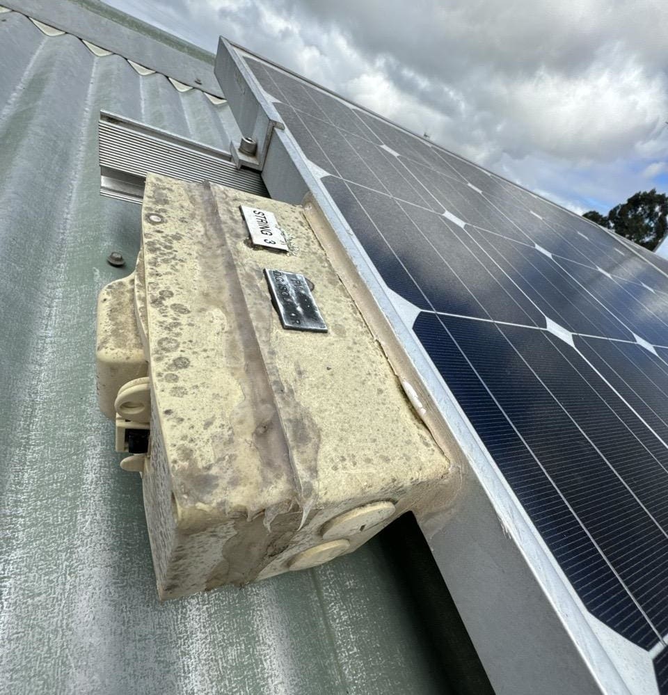 A rooftop DC isolator next to a solar panel on a roof.