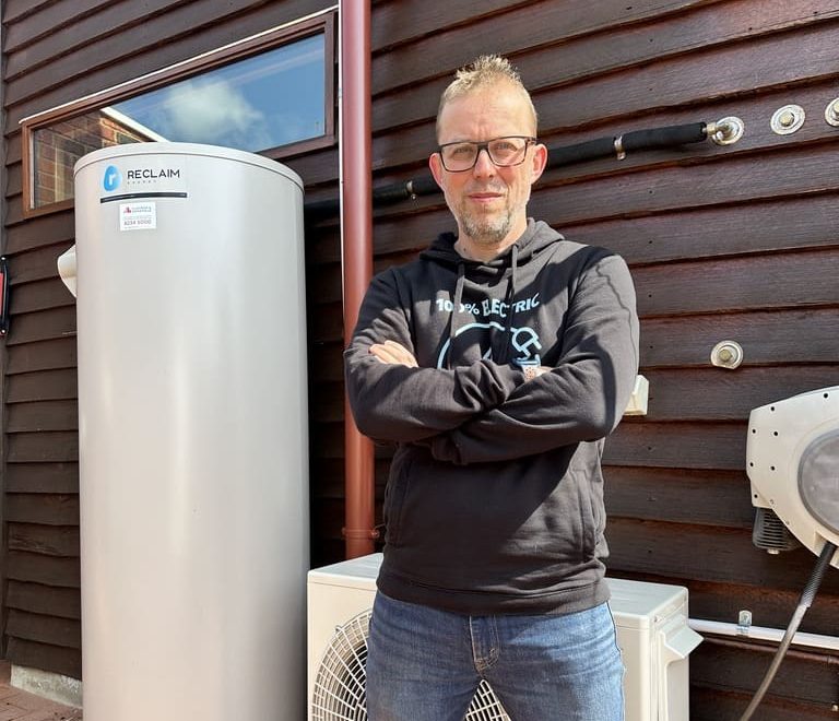 A man standing next to a hot water heat pump